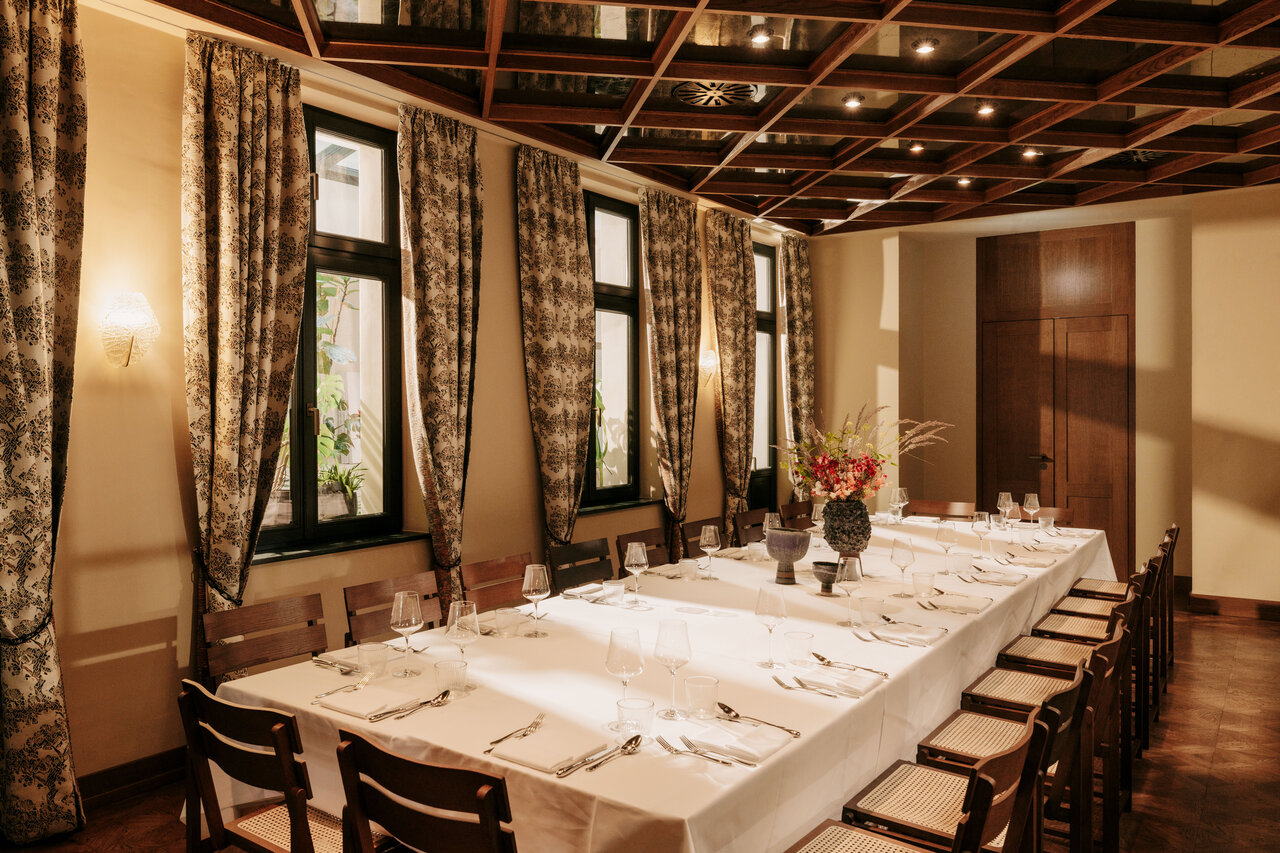 Blick auf die mit weißer Tischwäsche eingedeckte Tafel für zwanzig Personen im eleganten Private Dining Room des Château Royal, der als Eventlocation in Berlin Mitte zur Verfügung steht